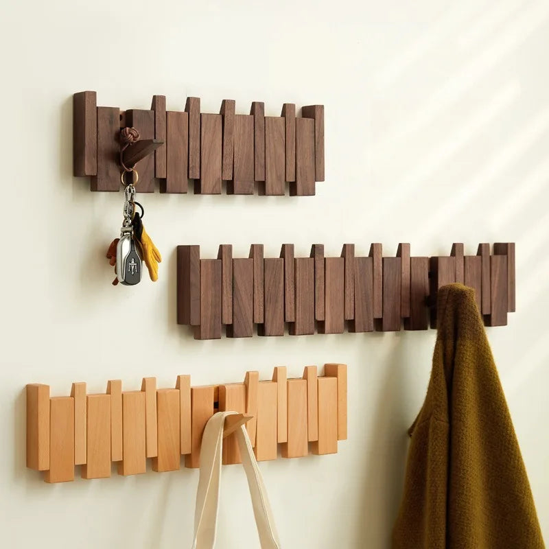 Three wooden wall hooks of different sizes on a light beige wall.