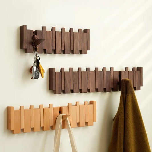 Three wooden wall hooks of different sizes on a light beige wall.